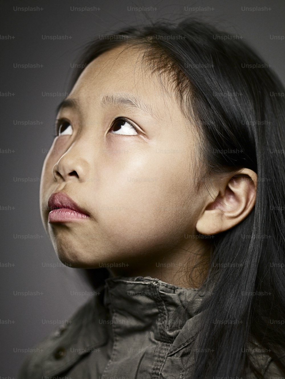 a young girl with long black hair looking up