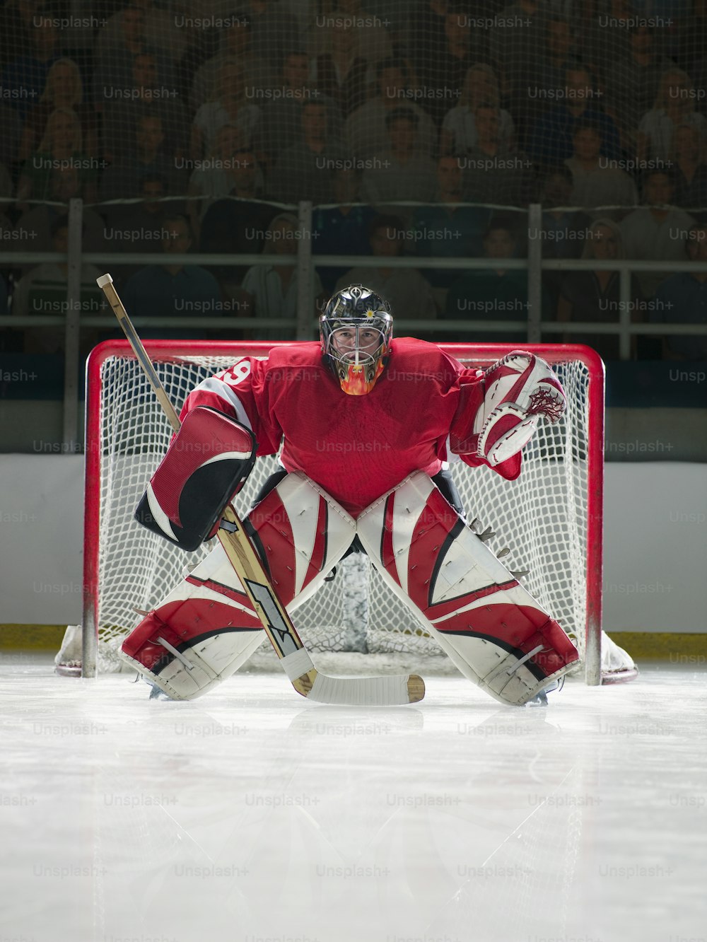 a hockey goalie sitting on the ice in front of a net
