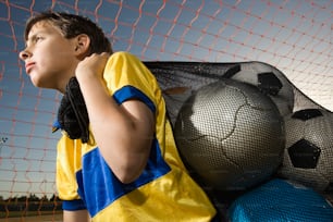 a boy in a yellow and blue shirt leaning against a net