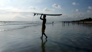 um homem segurando uma prancha de surf em cima de uma praia