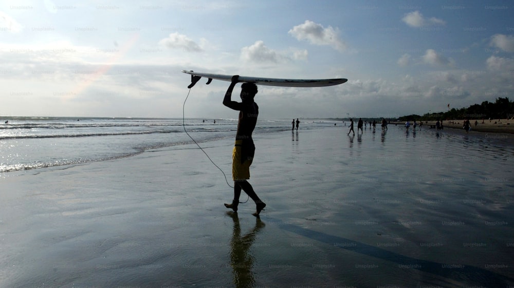Ein Mann, der ein Surfbrett auf einem Strand hält