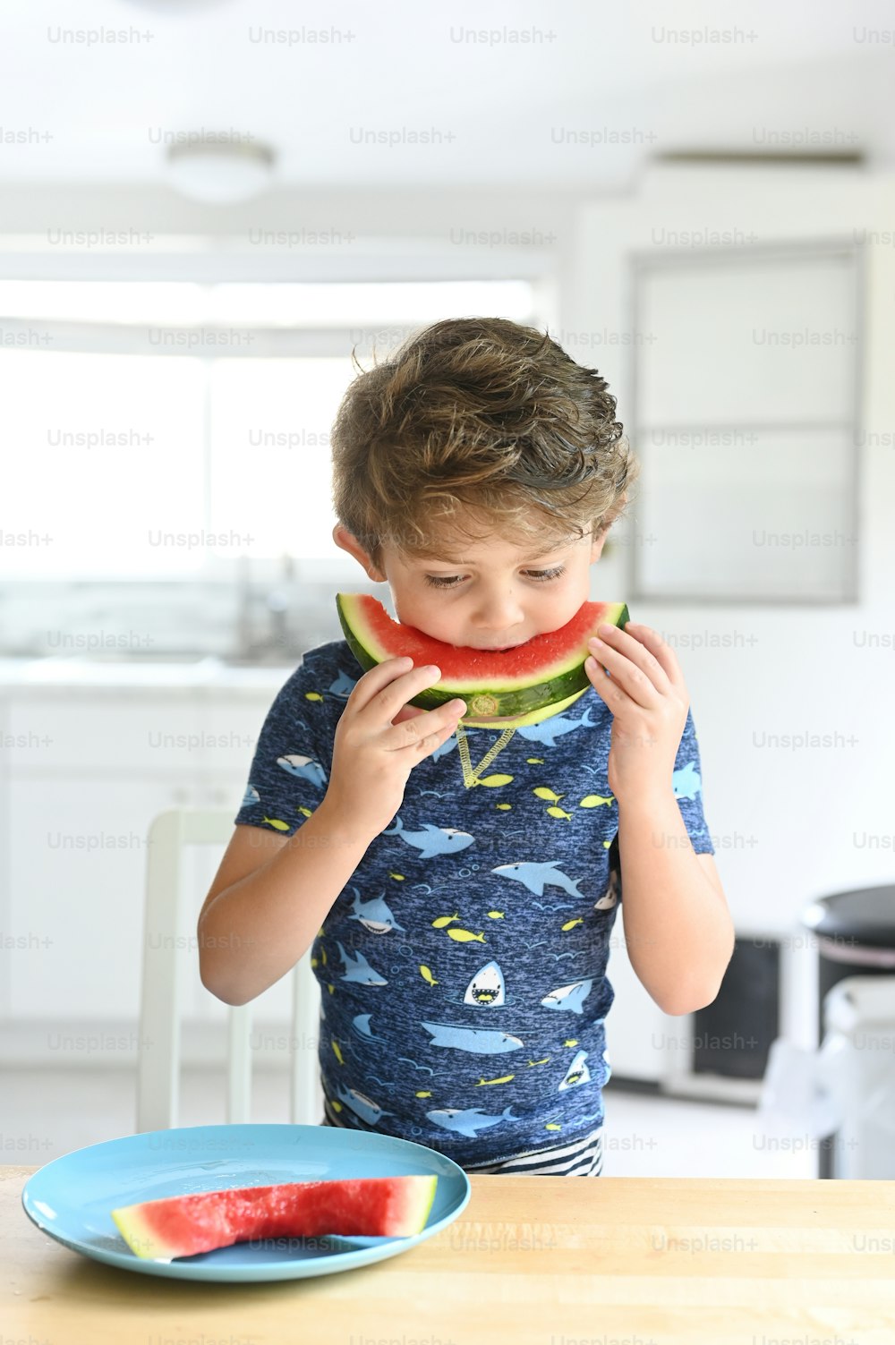 a young boy eating a piece of watermelon