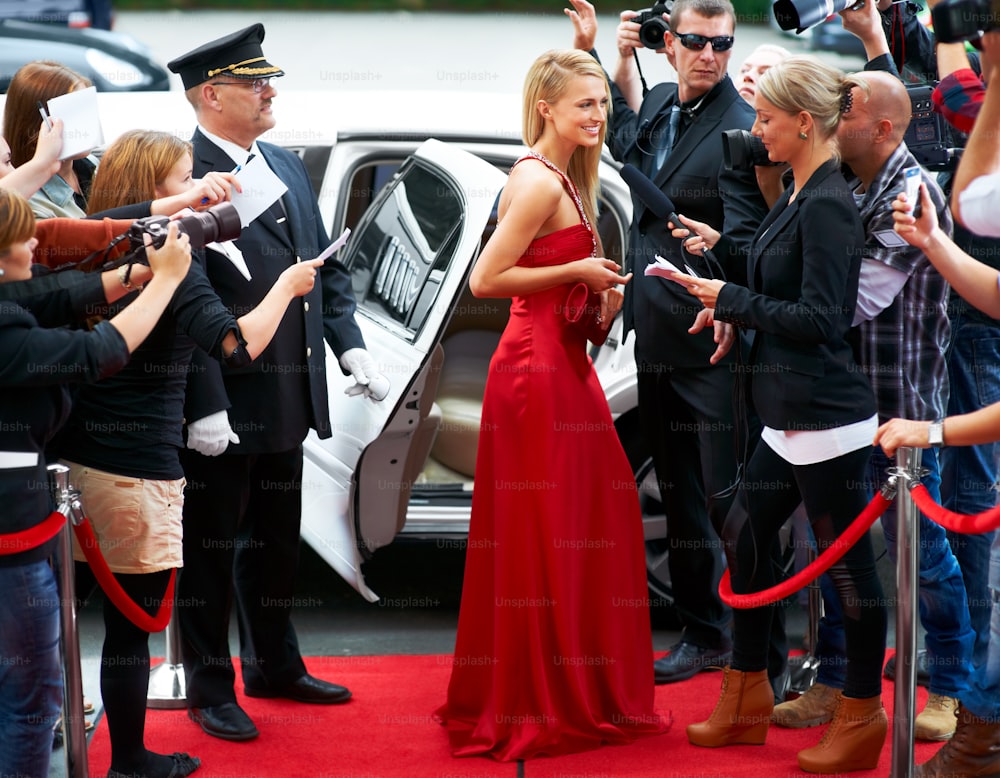 a woman in a red dress standing in front of a car