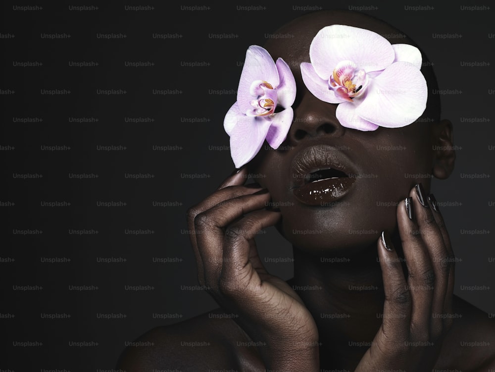 Una donna con due orchidee sul suo viso