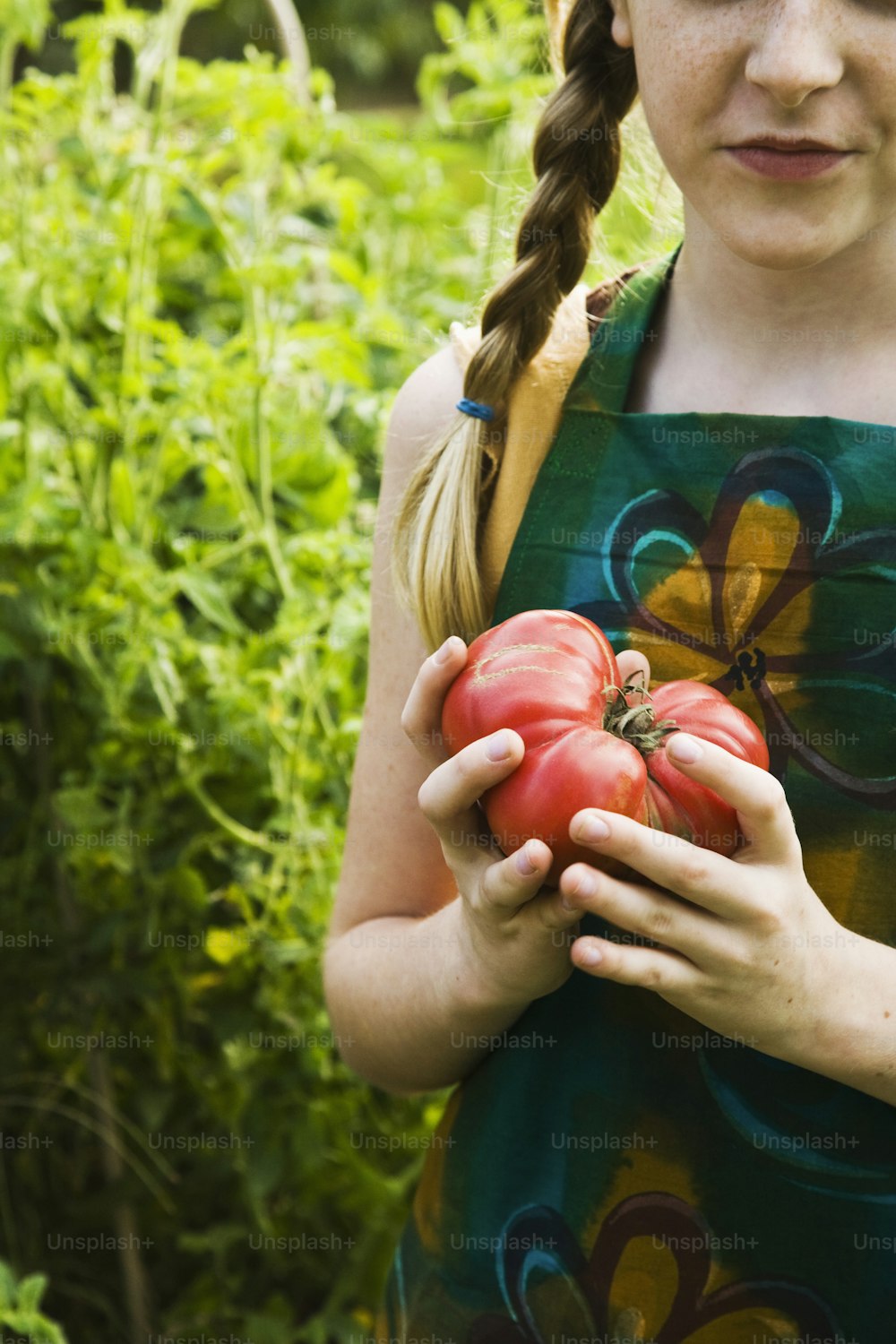 a young girl holding a bunch of tomatoes in her hands