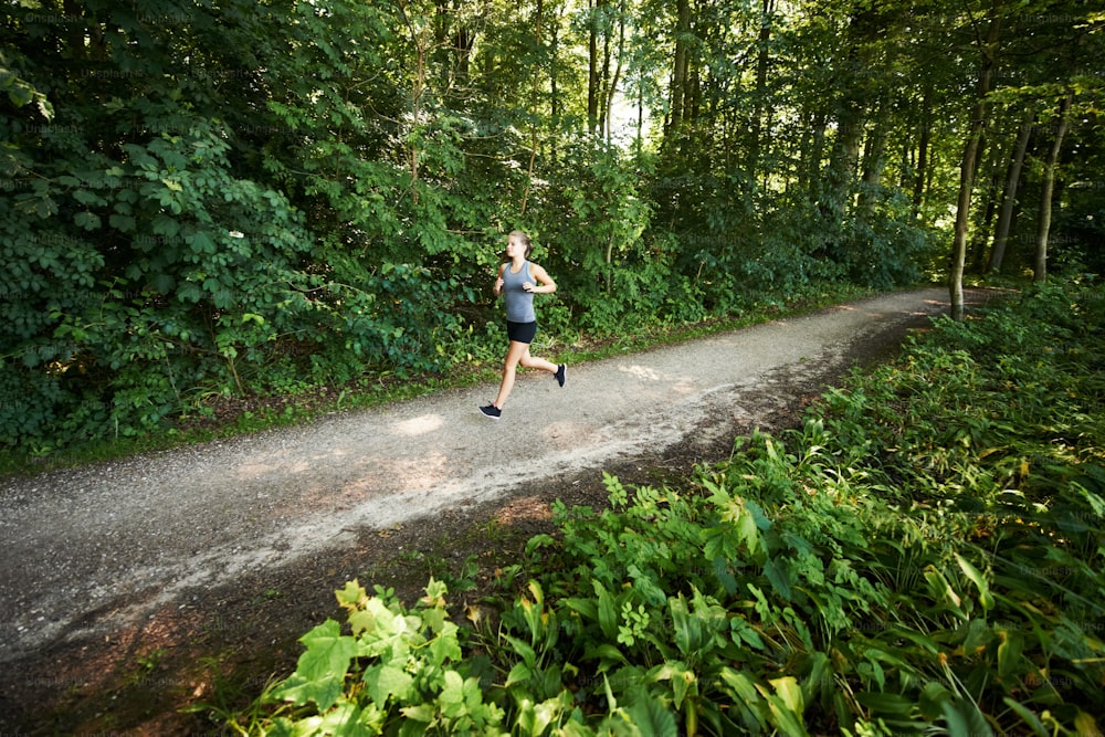 a man running down a dirt road in the woods