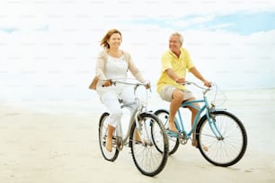 a man and a woman riding bikes on the beach