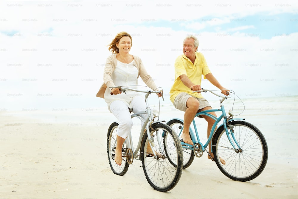 um homem e uma mulher andando de bicicleta na praia