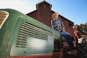 a man sitting on the front of a green tractor