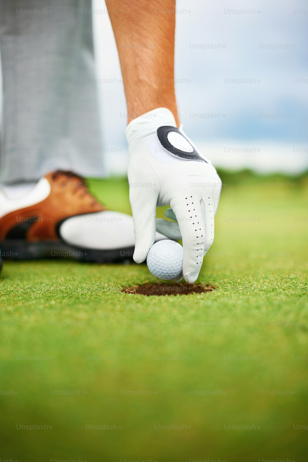 Closeup image of a golfer taking the ball out of the hole - Copyspace
