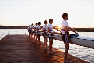 a group of people standing on a dock next to a body of water