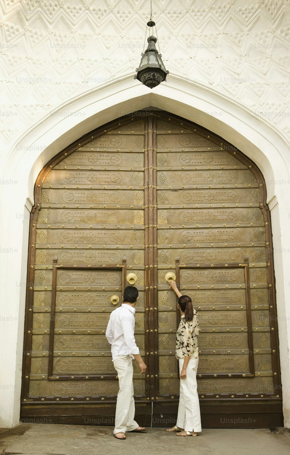 a man and a woman standing in front of a large wooden door