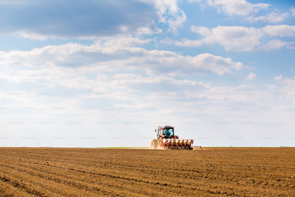 Farmer seeding, sowing crops at field. Sowing is the process of planting seeds in the ground as part of the early spring time agricultural activities.