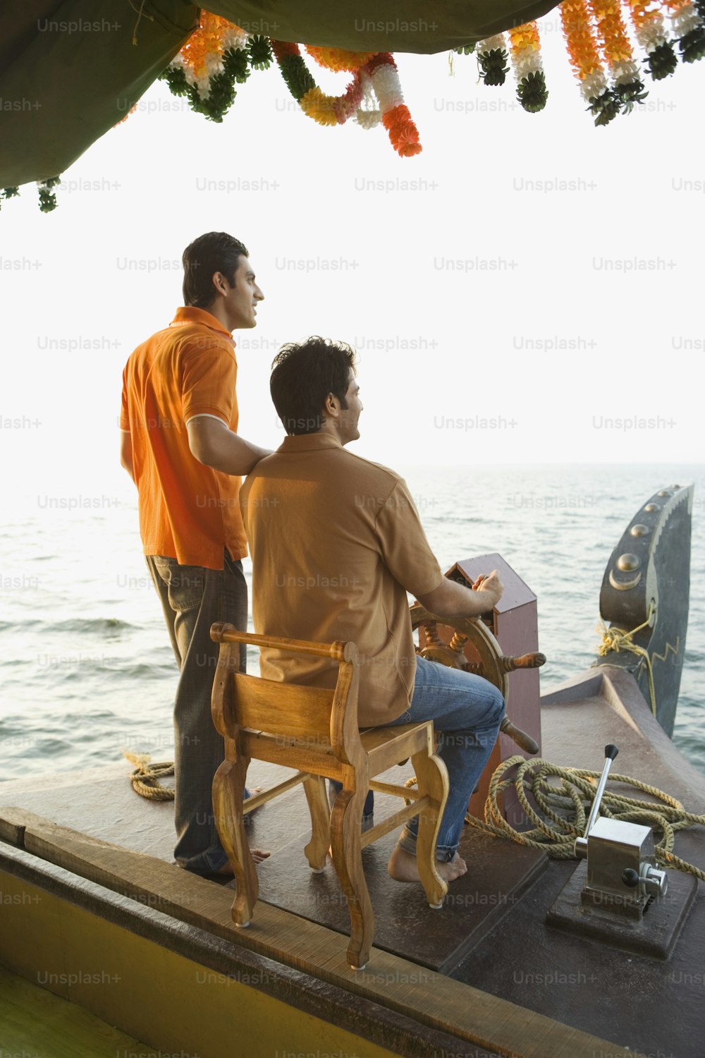 a couple of men sitting on top of a wooden boat