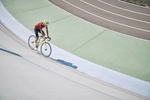 Top view of man in sports clothing cycling on track outdoors