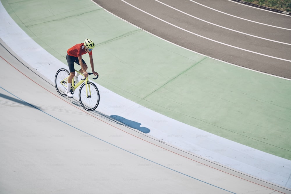 Vista superior de un hombre con ropa deportiva que anda en bicicleta en la pista al aire libre