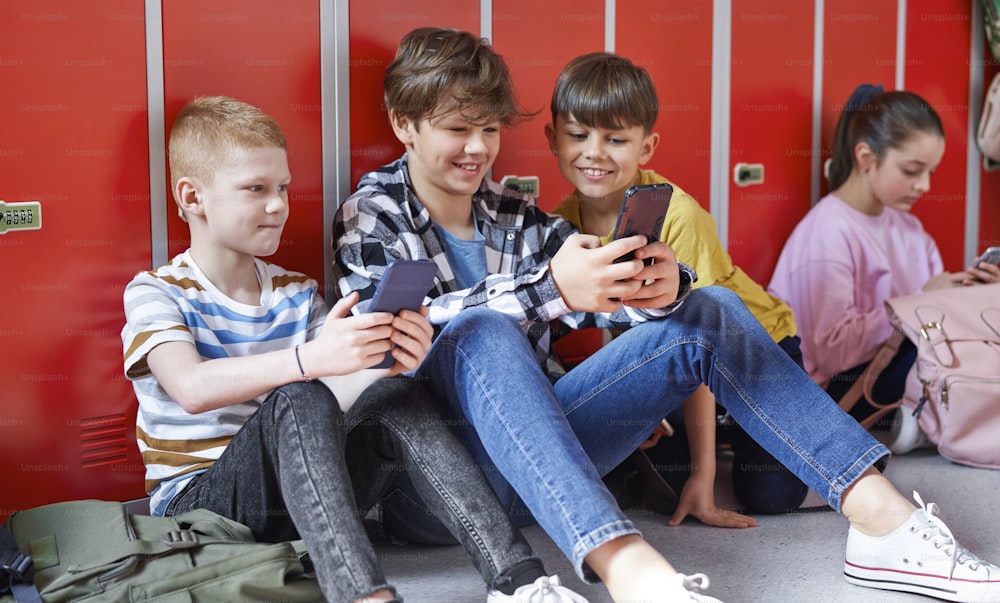 School children sitting and using smartphone at school