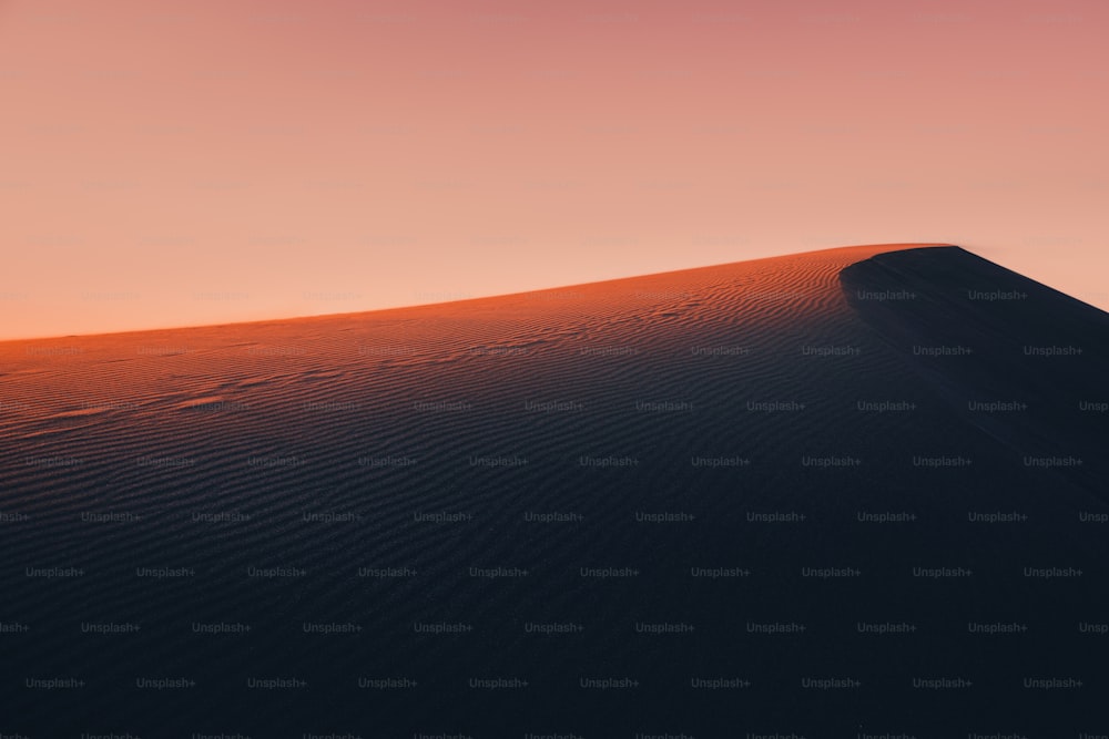 La luce atmosferica e mistica del raggio di sole del tramonto illuminava il pendio di una duna di sabbia da qualche parte nelle profondità del deserto del Sahara