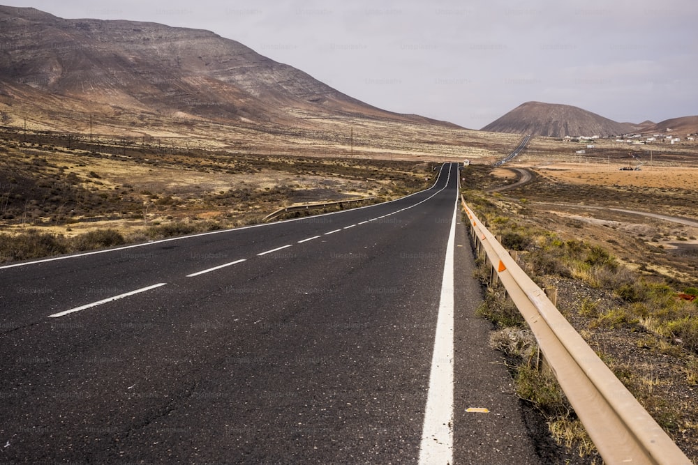 Largo camino recto en medio de un paisaje que no hay nadie en Fuerteventura para cruzar la isla y moverse. Estilo de vida alternativo con viento viviendo en un lugar donde nadie más se queda. Espíritu de aventura disfrutando de los viajes