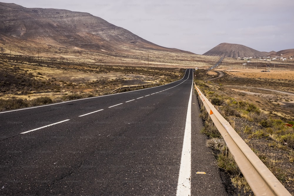 Lange gerade Straße mitten in einer Niemandslandschaft auf Fuerteventura, um die Insel zu überqueren und sich zu bewegen. Alternativer Wind-Lifestyle, der an einem Ort lebt, an dem niemand sonst übernachtet. Abenteuergeist am Reisen