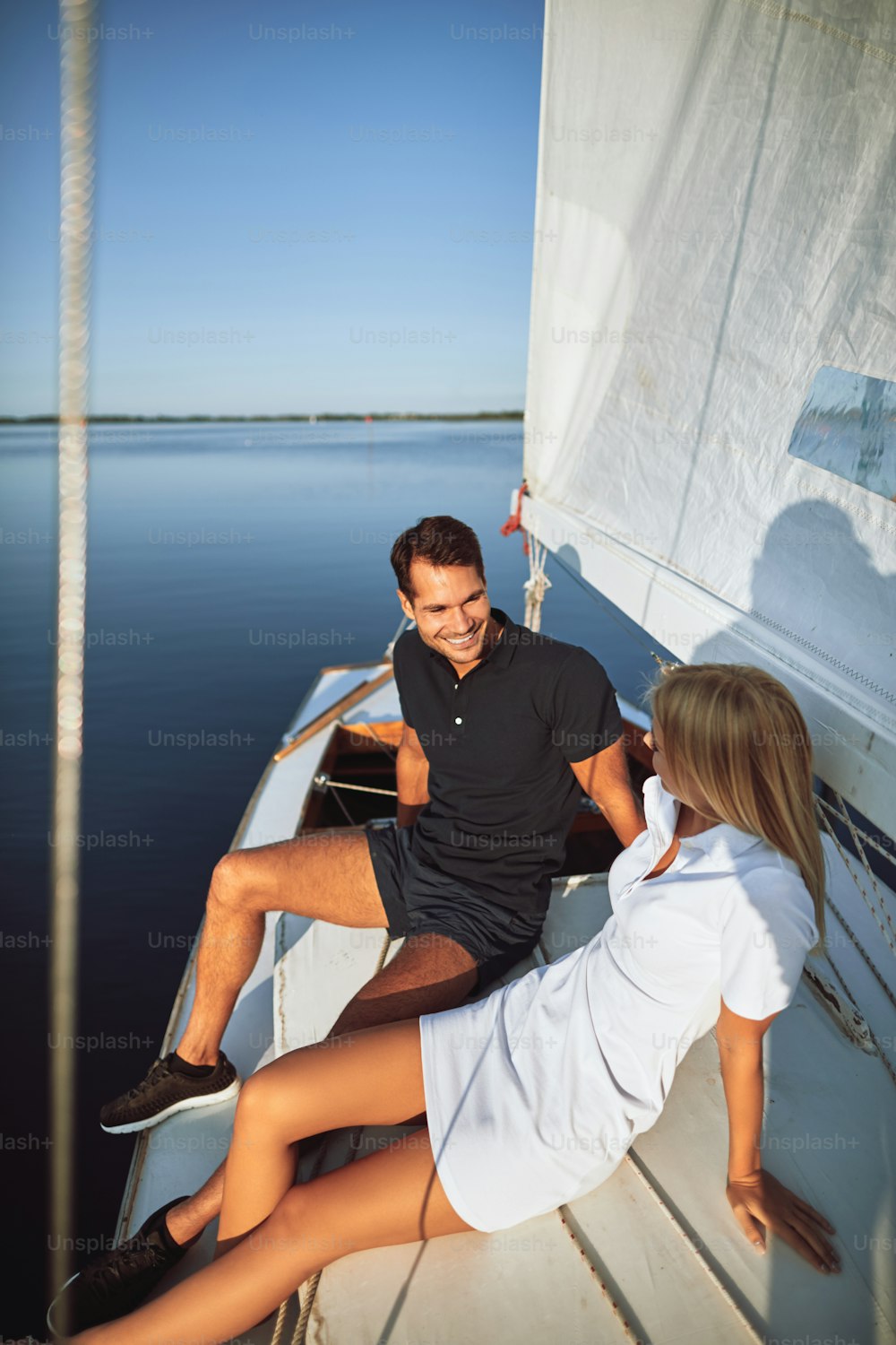 Smiling young couple sitting together on the deck of their yacht while enjoying an afternoon sailing