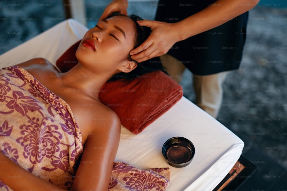 Massage au spa. Mains massant la tête de la femme au salon de beauté thaïlandais. Fille asiatique appréciant la massothérapie. Haute résolution
