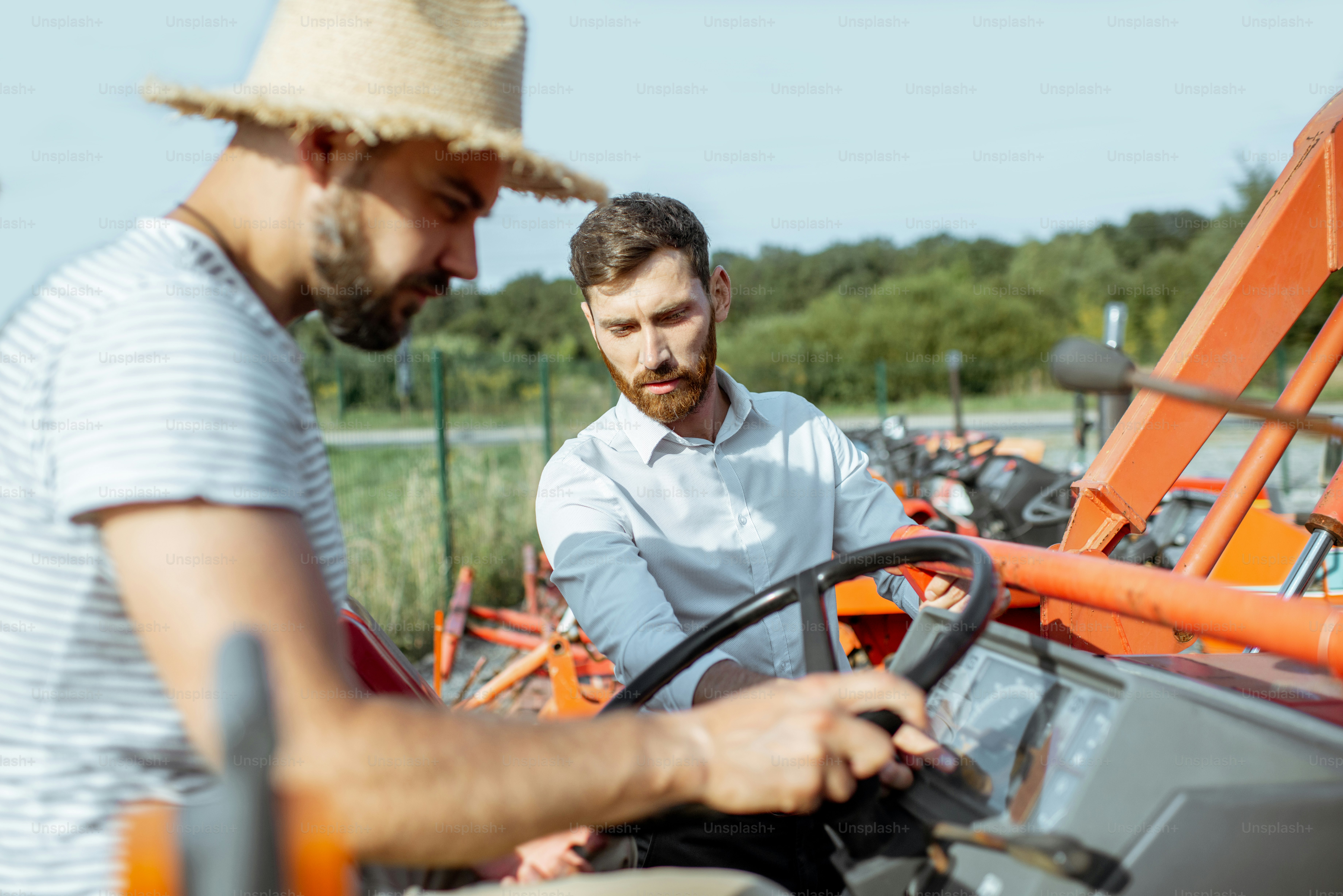 Jovem agrônomo com vendedor elegante escolhendo um trator para a agricultura no terreno aberto da loja agrícola
