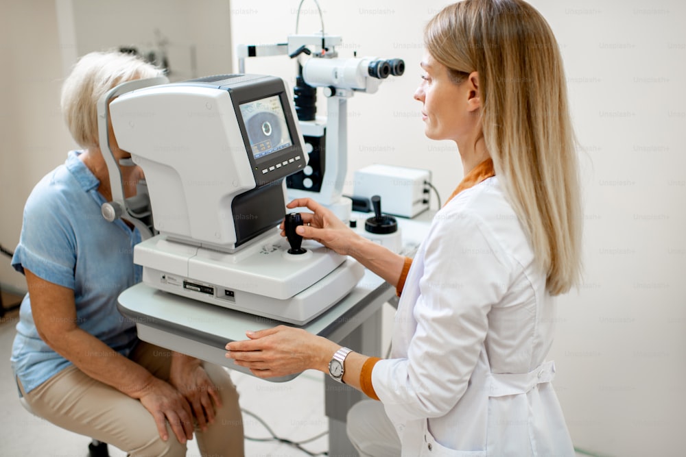Oftalmólogo examinando los ojos de un paciente mayor con microscopio digital durante un examen médico en el consultorio oftalmológico