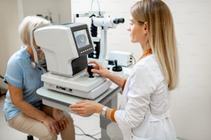 Ophthalmologist examining eyes of a senior patient using digital microscope during a medical examination in the ophthalmologic office