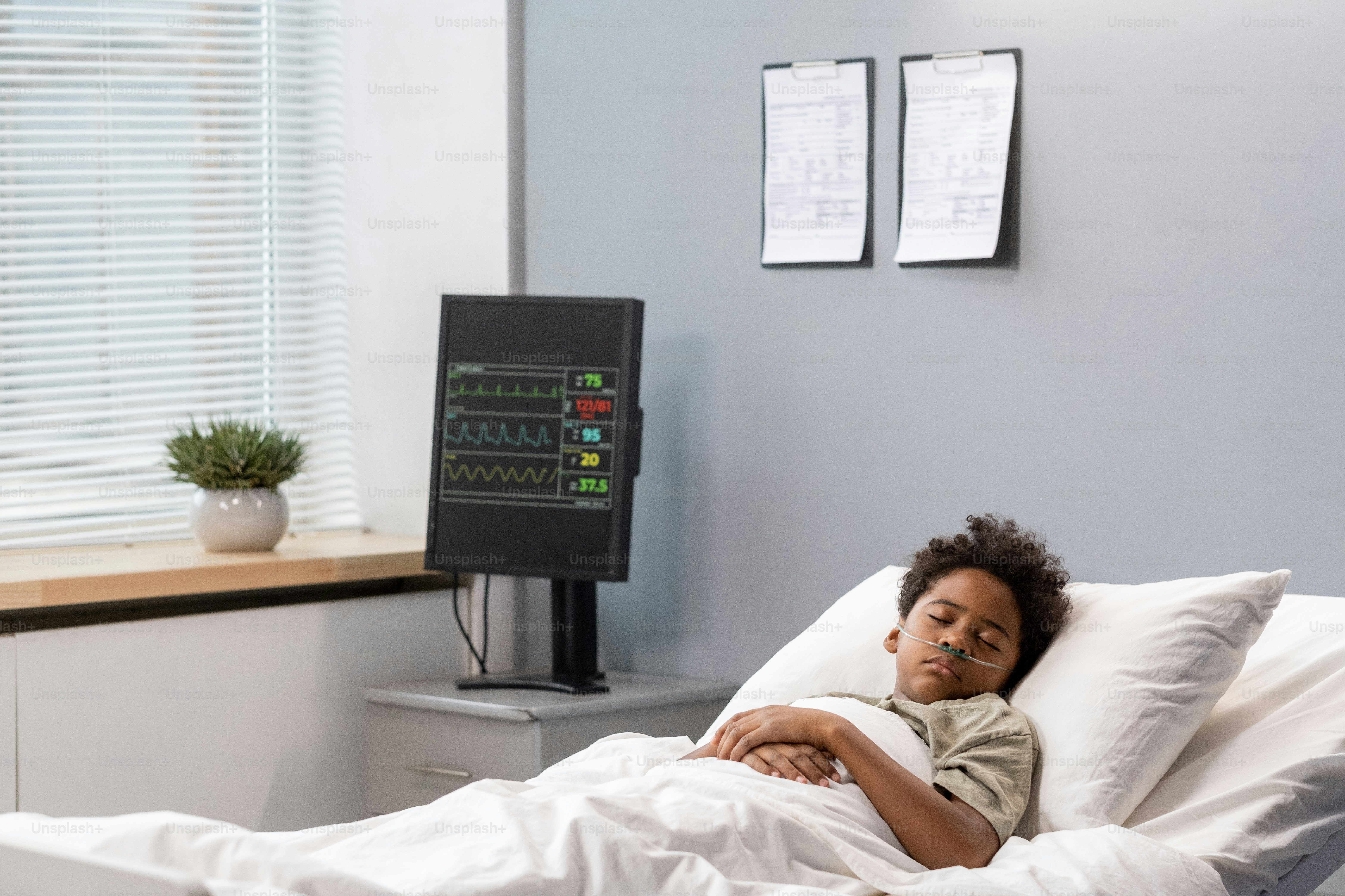 Sick little boy sleeping in bed at hospital ward during his disease