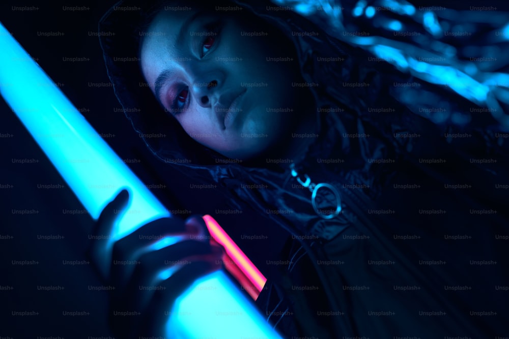 Retrato da adolescente asiática jovem na luz neon vermelha. Conceito de retrato cibernético e futurista, olhando para o futuro