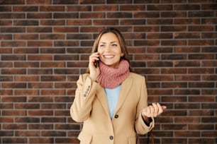 Eine modische Geschäftsfrau, die vor einer Ziegelmauer steht und telefoniert. Wirtschaft und Telekommunikation. Eine Geschäftsfrau, die das Telefon benutzt.