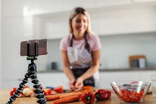 Close-up of smart phone on tripod. Housewife filming herself how to prepare healthy lunch during corona virus quarantine.