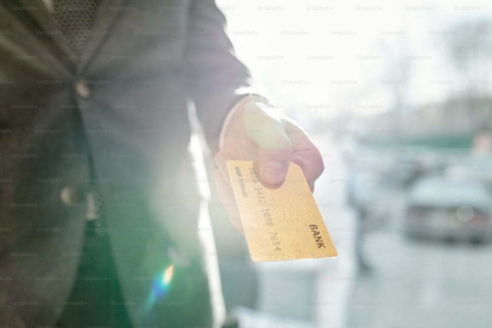 Close-up of unrecognizable businessman giving credit card while paying in store, lens flare effect