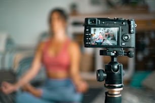 Junge Frau, die zu Hause trainiert, Pilates macht und sie mit einer Digitalkamera aufzeichnet, um Workout zu unterrichten und Web-Klasse zu produzieren - Content Creator Business Free Healthy Lifestyle People Konzept