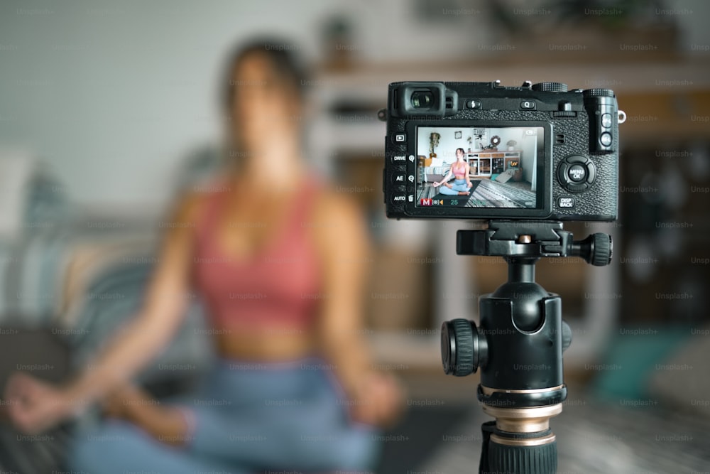 Giovane donna che si esercita a casa facendo pilates e registrando a lei con fotocamera digitale per insegnare allenamento e produrre lezioni web - concetto di persone di stile di vita sano gratuito per creatori di contenuti aziendali