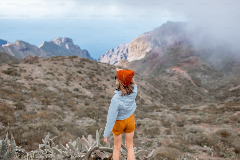 Young stylish woman enjoying beautiful landscapes, traveling highly in the mountains on Tenerife island, Spain