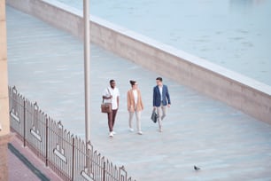 Above view of interracial business students walking on embankment and discussing new projects