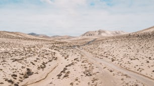 Path road in the middle of a mountains sand desert with blue bright sky in background. Concept of desertification or climate change for global warming. Amazing scenic travel destination