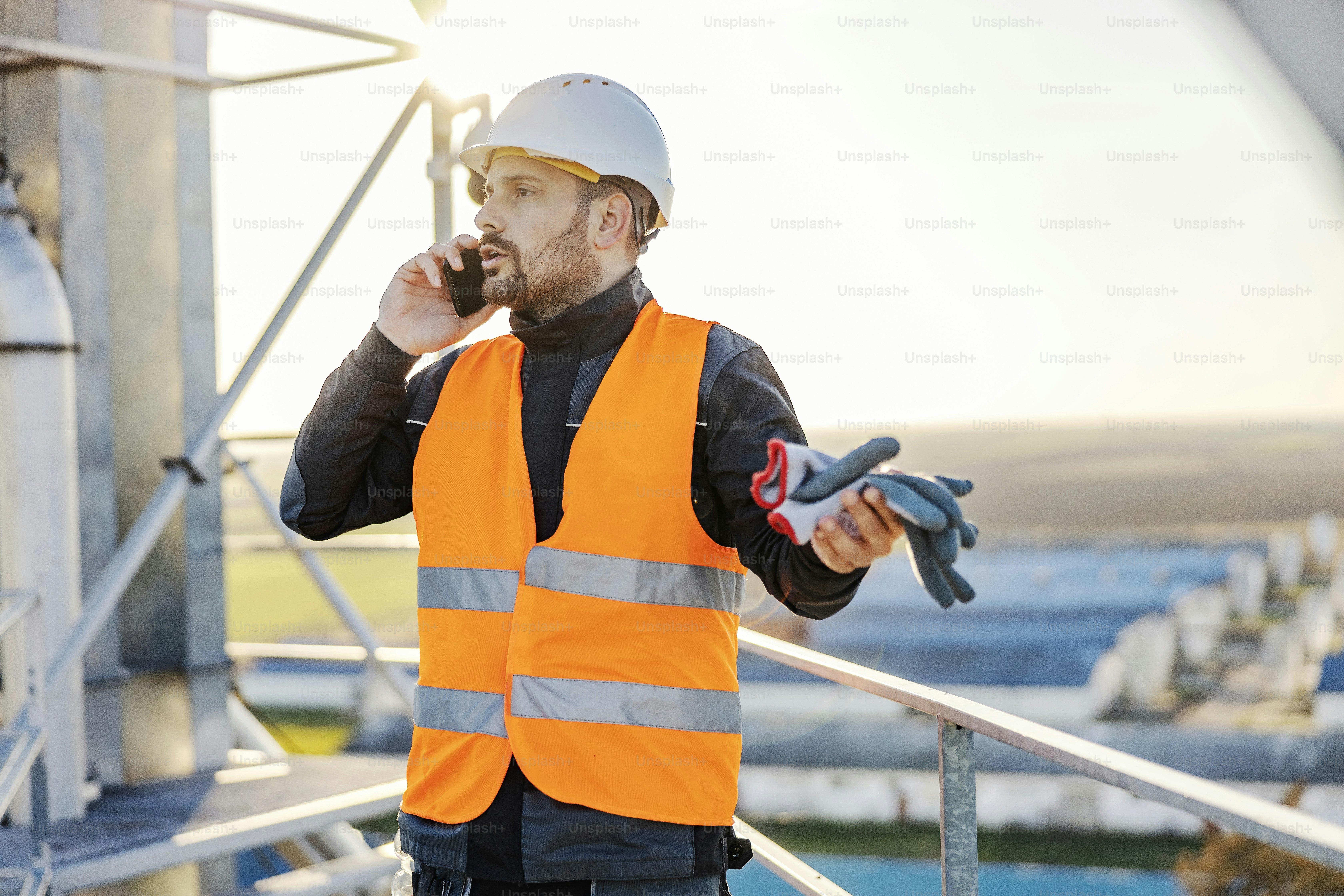 An industry worker on height having phone call with manager.
