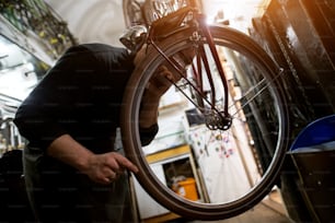 Mann nimmt die Radwucht des Fahrrads in der sonnigen Werkstatt unter die Lupe.