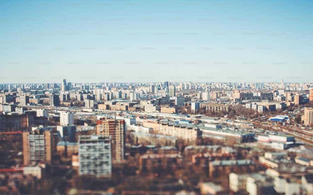 True tilt-shift view form hight point of the urban cityscape: a residential district with many houses of different size and color, cold bright day with blue sky, focus in the middle of the image