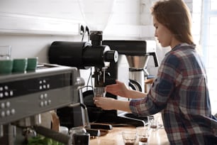 Gros plan d’une femme barista à l’aide d’un moulin, faisant du café frais