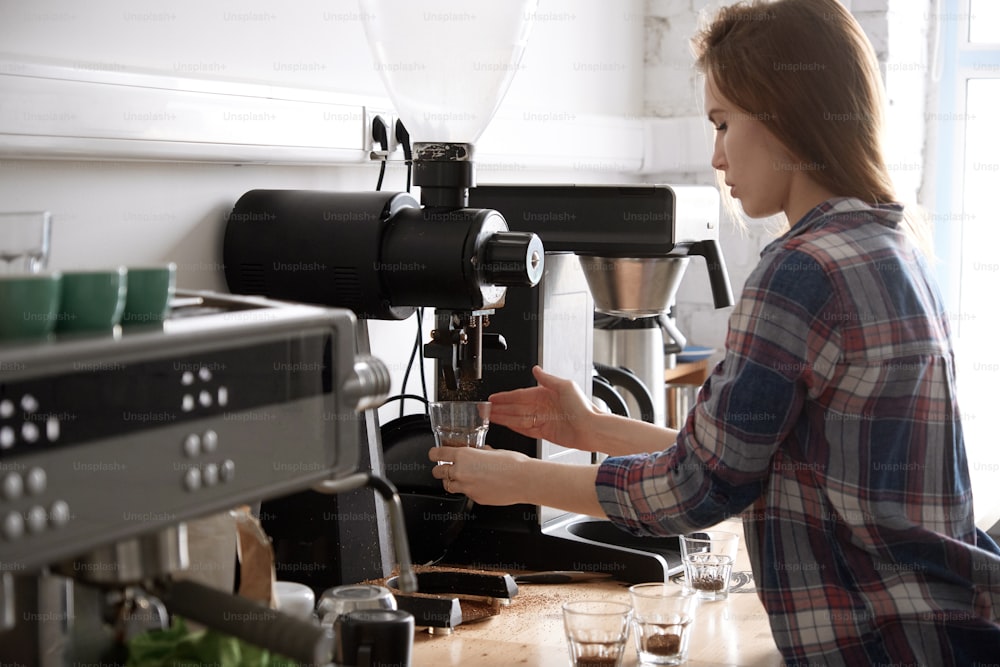 Close up of female barista using grinder, making fresh coffee