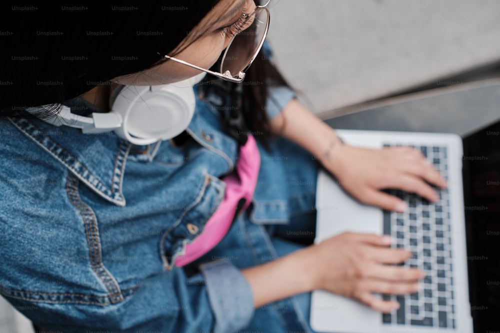 Close up of a girl in denim clothes typing on her laptop.