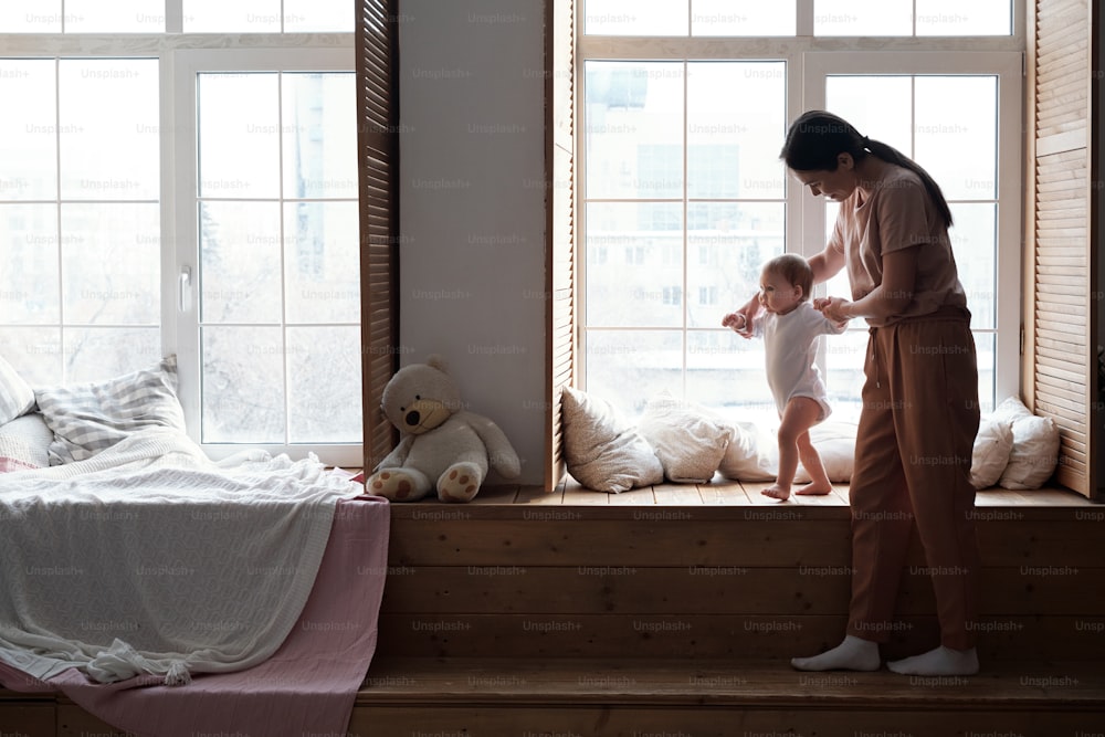 Foto longa de uma jovem mãe moderna passando tempo em casa com sua adorável filha ensinando-a a ficar de pé e andar