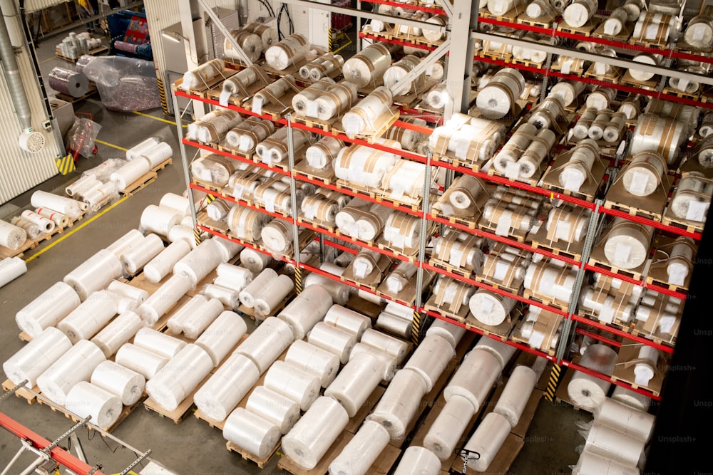 Many rolled polyethylene film units on shelves and racks inside warehouse of large modern factory