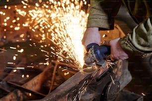 工場内の金属研削にグラインダーを使用する作業者のクローズアップ