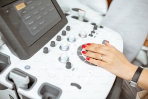 Medico che controlla la macchina ad ultrasuoni durante l'esame del paziente. Vista ravvicinata sulla mano e sui pulsanti