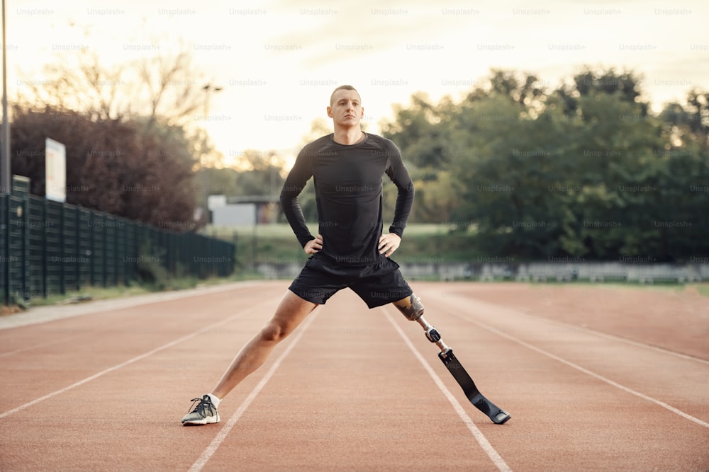 Um desportista em forma com treino de pernas protéticas no estádio.